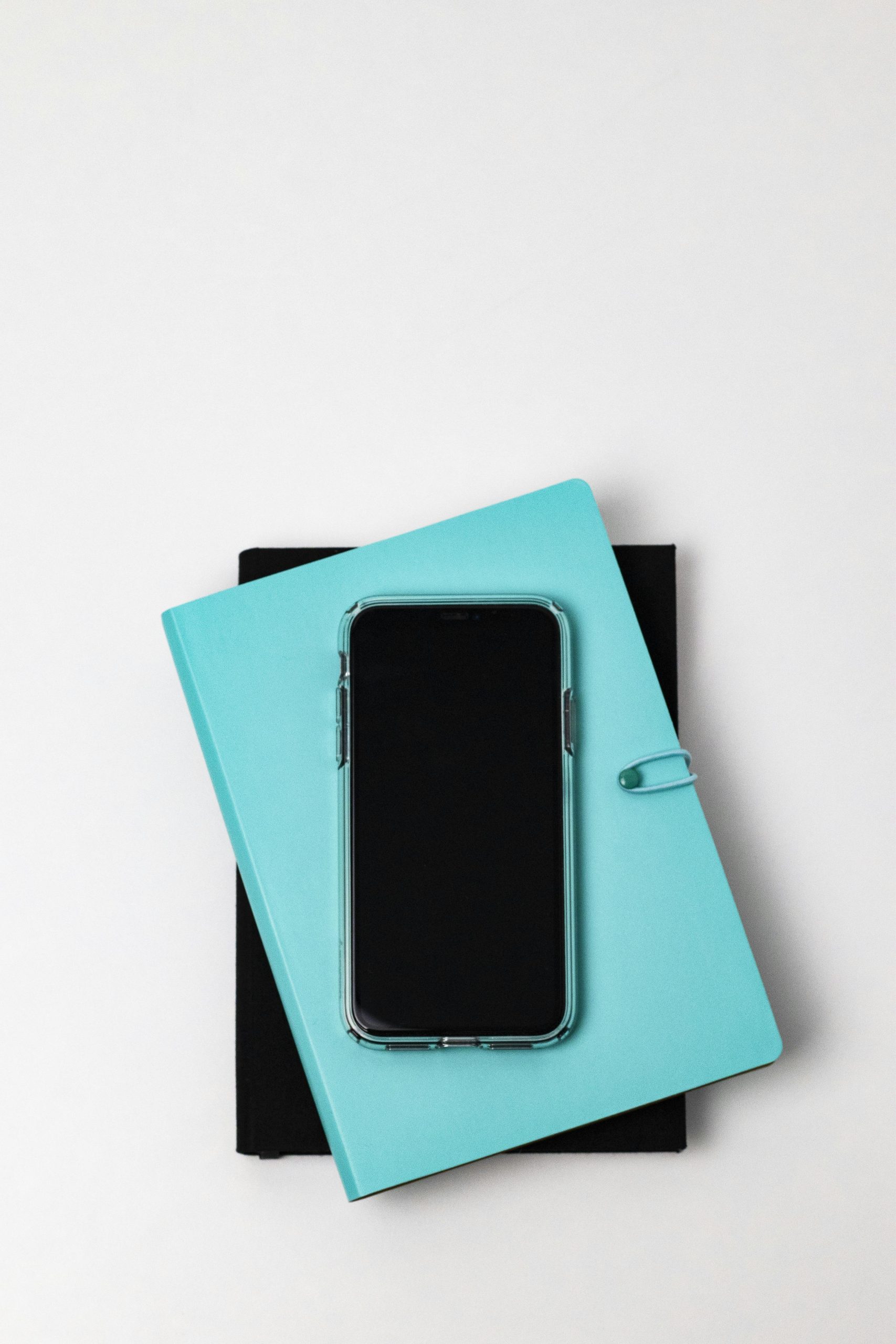 A smartphone placed on stacked notebooks with ample copy space in a minimalist composition.